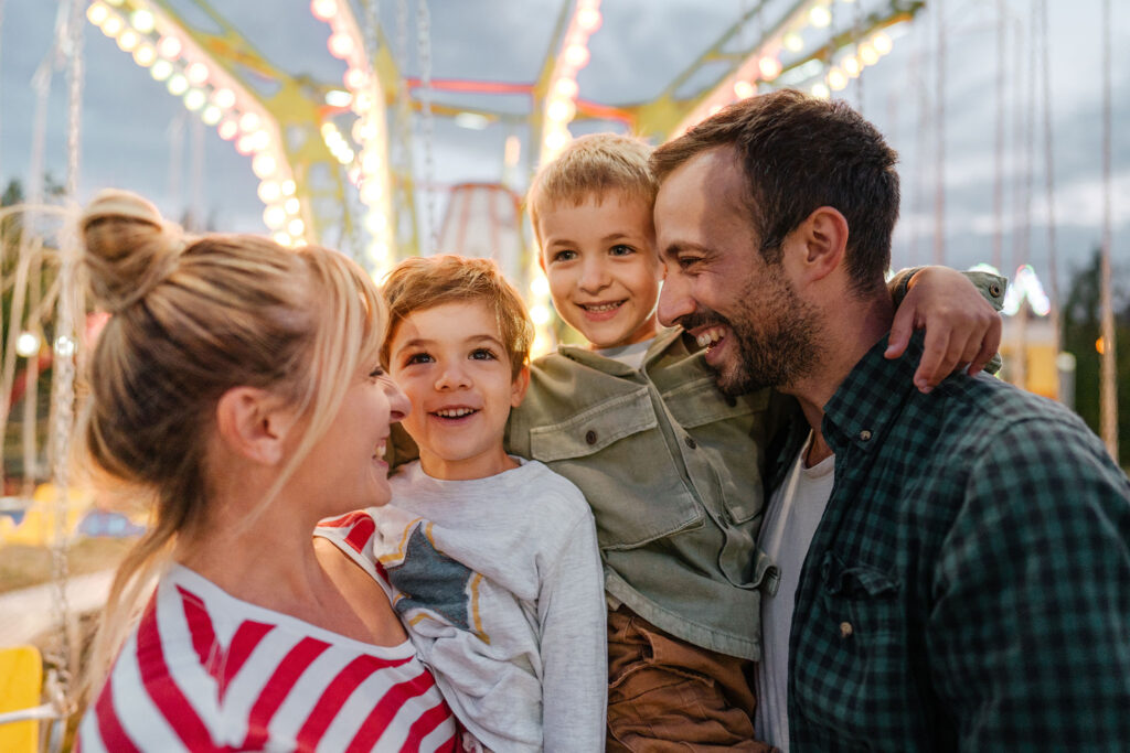 A family of four shares a laugh at an amusement park.