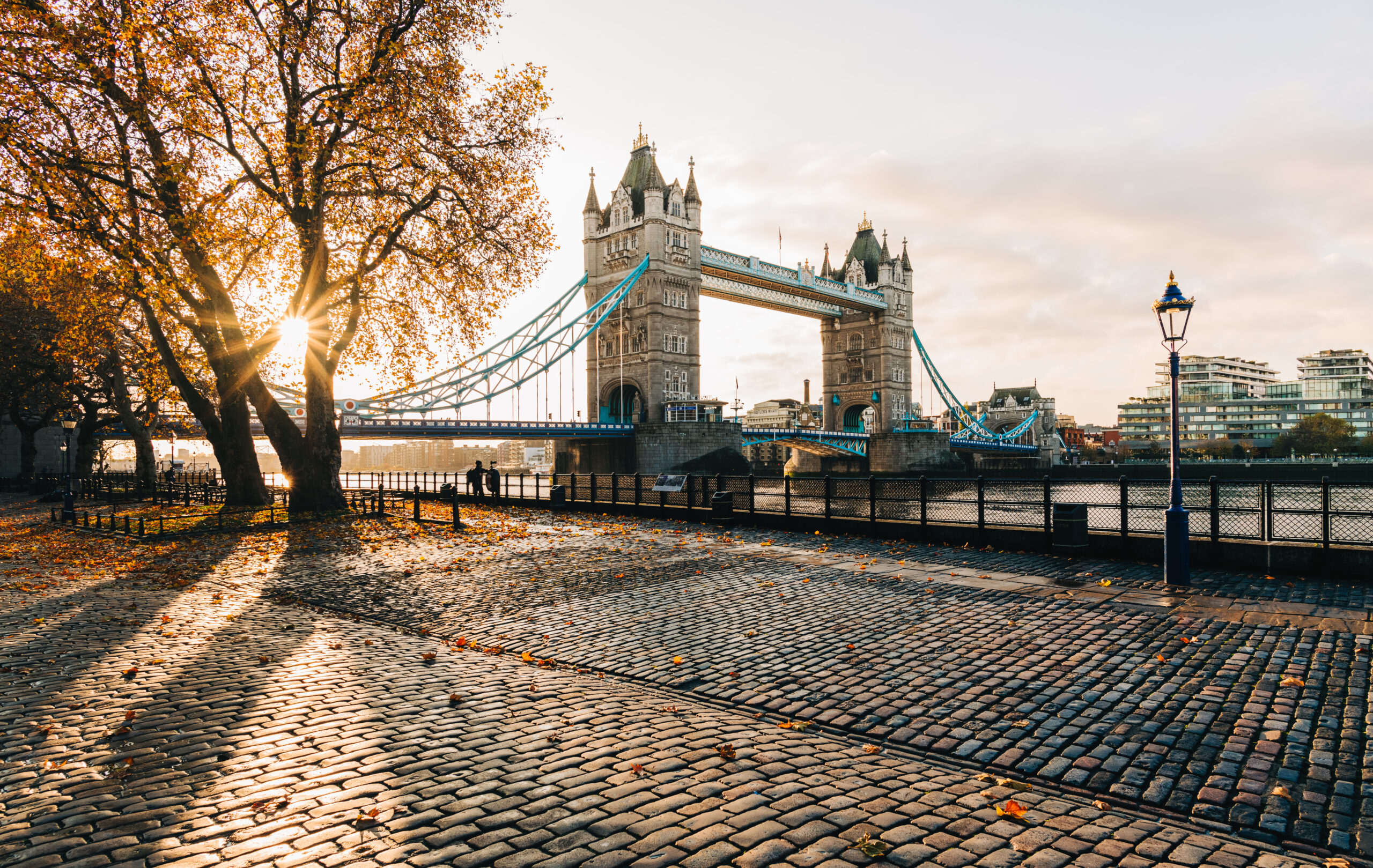 Sunrise illuminates autumn leaves at London's Tower Bridge.