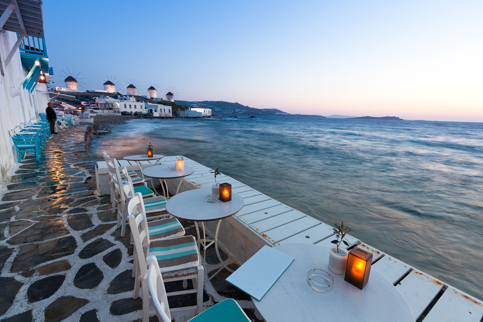 Tables and chairs overlook the Mediterranean at dusk in Mykonos.