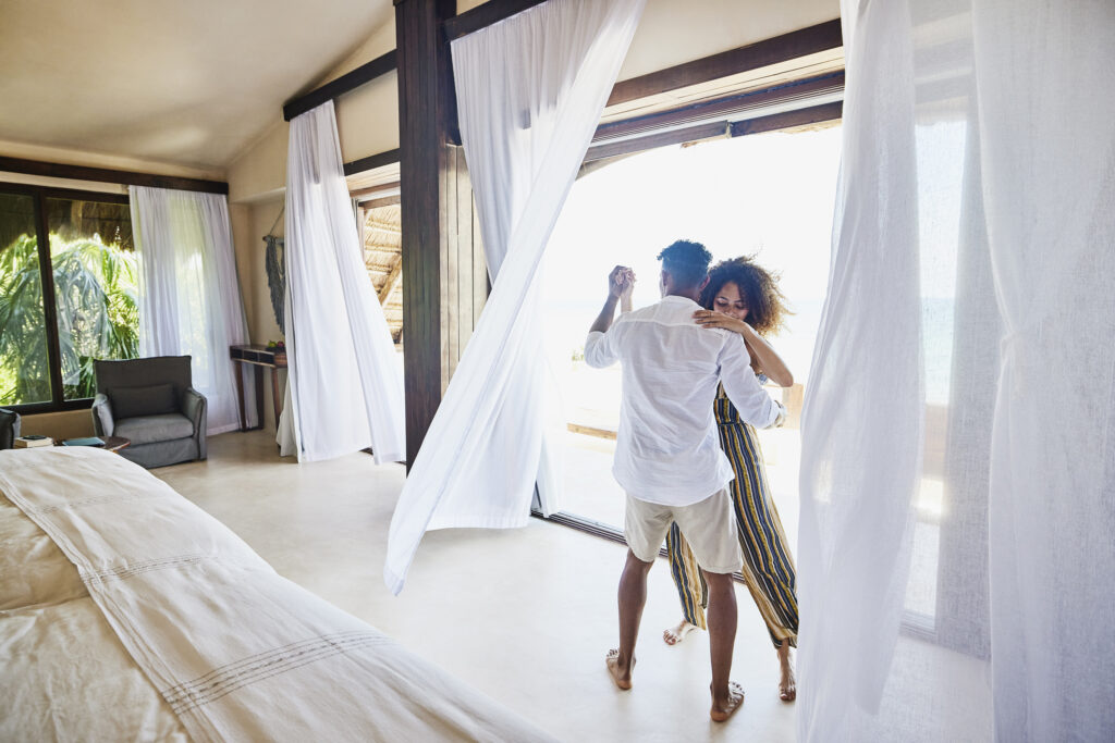 Wide shot of couple dancing in luxury suite of tropical resort