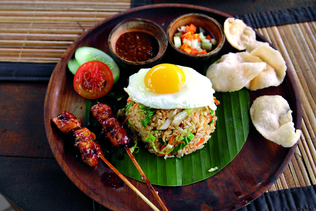 Spicy fried rice with prawns, vegetable, fried chicken, fish cracker, pickle and chicken satay, topped with fried egg and dried scallop-anchovy chili sambal